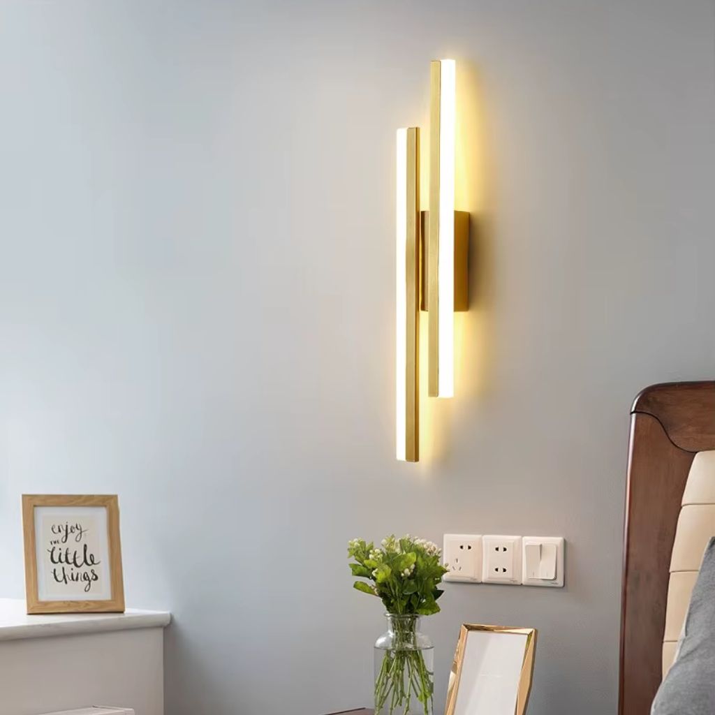 Modern wall sconce on a gray wall with decorative elements below.